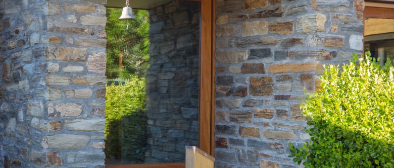 Entry featuring a striking combination of schist stone and a sleek glass door, creating a welcoming and modern first impression.