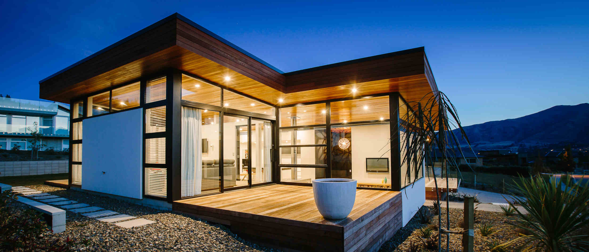 View of a modern house featuring a bold, chunky cedar roof and fascia. The cedar seamlessly extends indoors, creating a continuous flow between exterior and interior, giving the illusion of a floating roof and ceiling.
