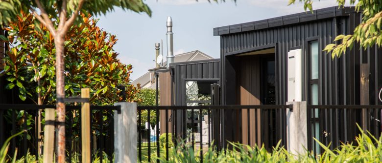 Side view of the house through a fence, highlighting the contrasting cladding of ColourSteel and Cedar.
