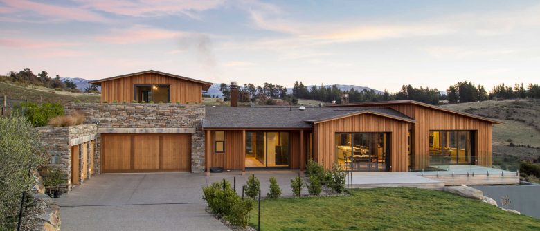 Side view of the house at dusk with an apartment above the garaging and big, wide decks.