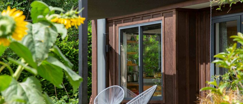 Detail of the front of a small two-story home with a mezzanine bedroom, featuring vertical ply board and batten cladding