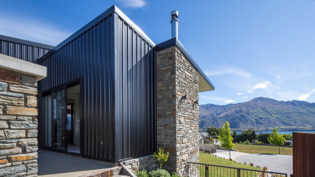 Side view showcasing the juxtaposition of black Colorsteel and natural schist cladding.