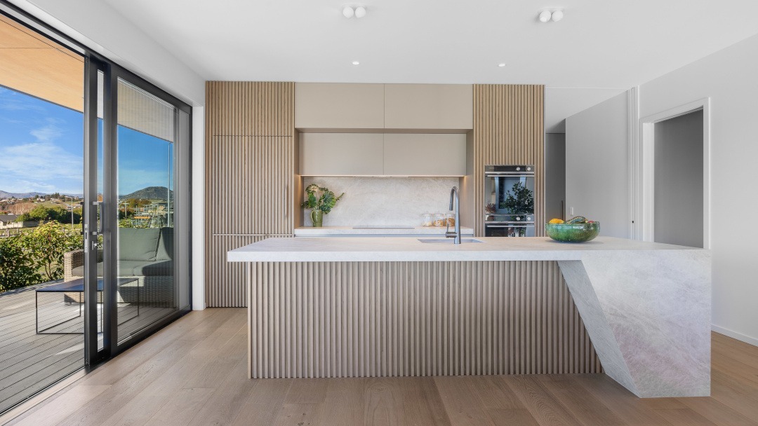 Interior view looking toward the bespoke kitchen by CABINETree, featuring custom cabinetry at the heart of the open-plan living space.