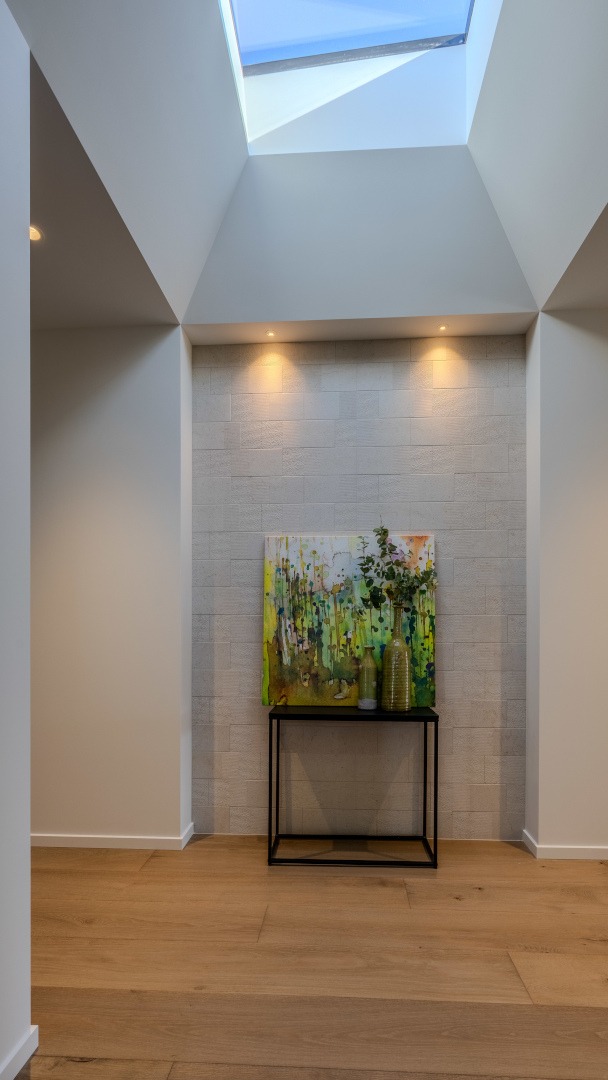 Spacious, light-filled hallway linking living and private areas, with sky-light, and custom detailing enhancing the sense of flow and openness.