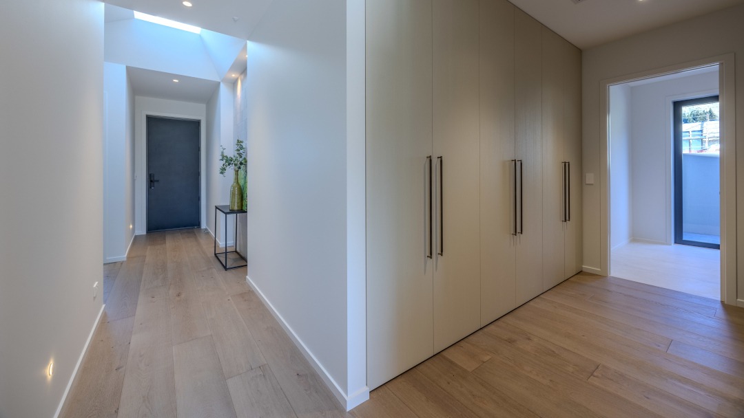 View of internal linking passages featuring warm materials, and custom joinery connecting the main living spaces and private rooms.
