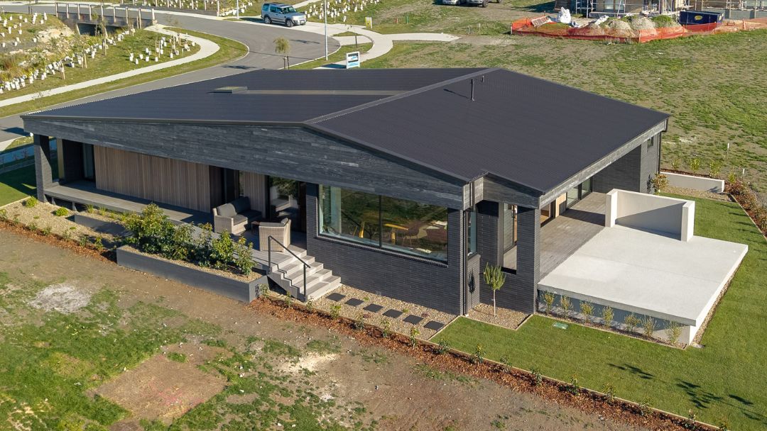 Aerial view of the house showing its north-facing orientation, rooflines, surrounding landscaping, and integration with the natural Wānaka setting.