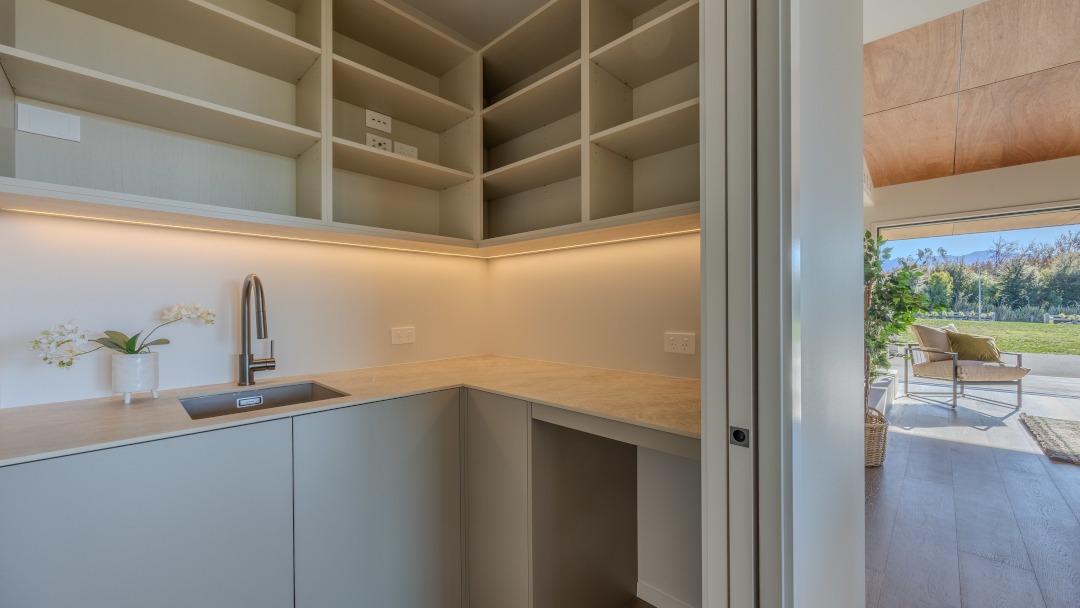 View of the pantry tucked behind the kitchen, featuring functional cabinetry, ample storage, and a clean, streamlined design.