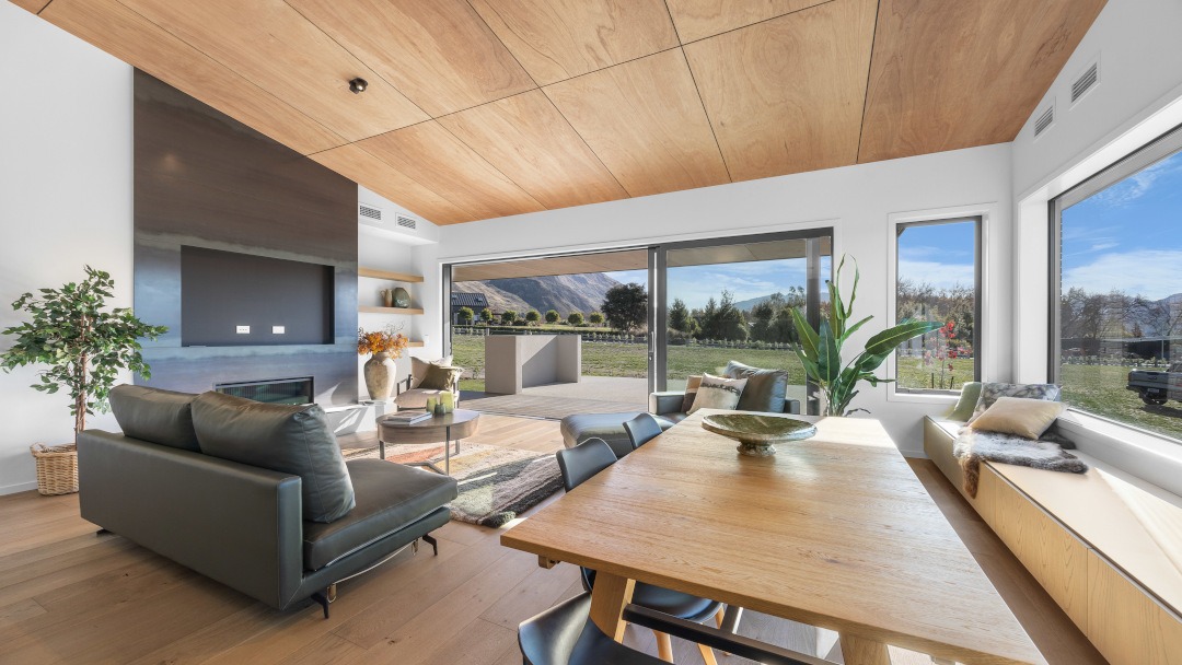 View across the dining table toward the living area, with large windows framing a stunning mountain view beyond.
