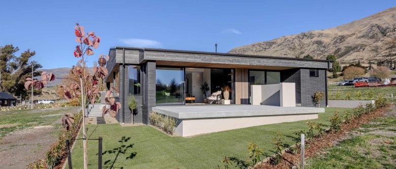 North-facing view across the deck toward the front of the house, large windows, and clean architectural lines under a wide eave.