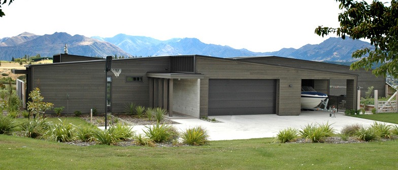 Entry and garage view of house, showcasing exterior cladding of horizontal cedar weatherboards and board-formed tilt-slab concrete.