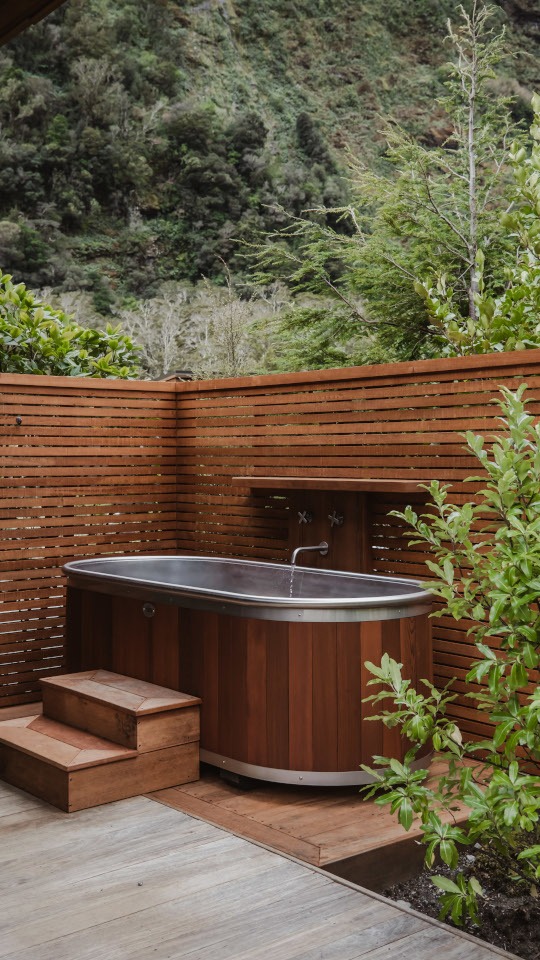 Outdoor bath enclosed in cedar slats, offering a private, natural bathing experience surrounded by warm timber textures.