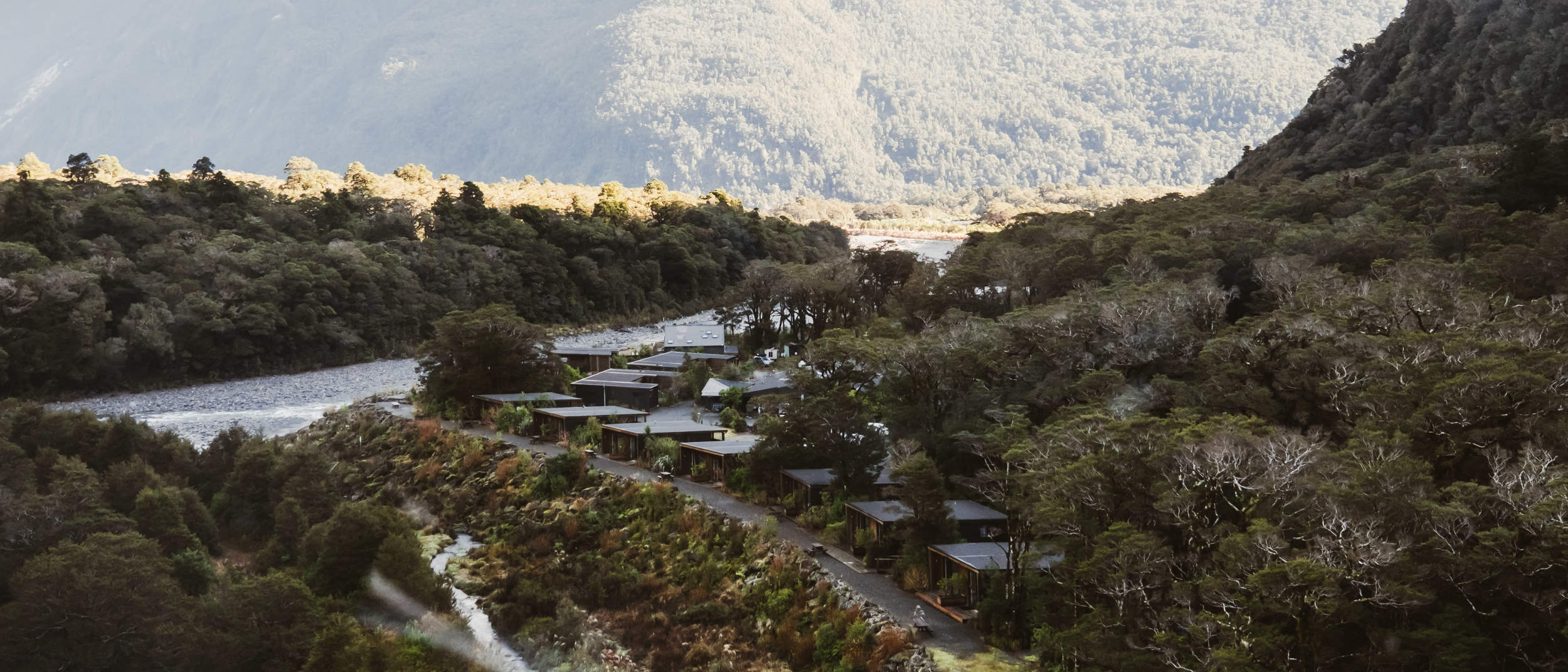 Aerial view of Milford Sound Lodge in winter, surrounded by, native bush, and dramatic mountain scenery.