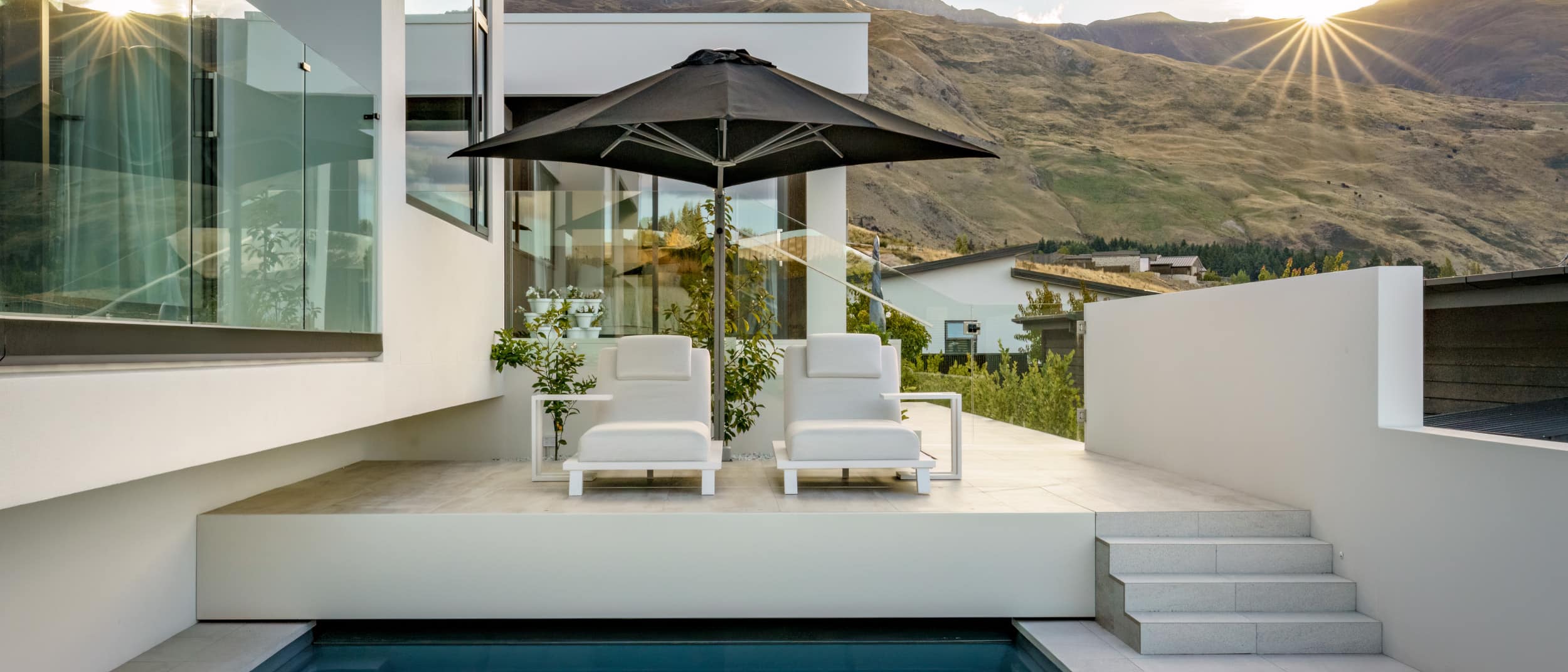 Sun setting behind the hills over the pool area of Opal House, creating a warm evening atmosphere.
